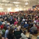 A massive crowd fills a high school gym.