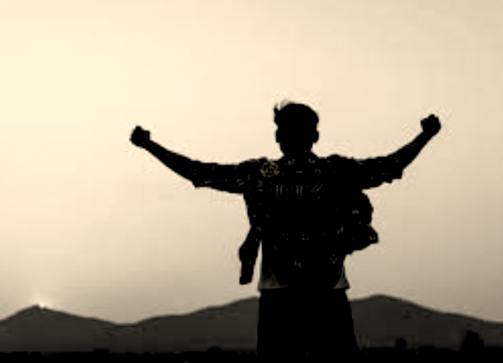 The outline of a man looking at a sunrise, his arms raised in triumph.