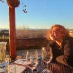A woman sits on an outdoor patio, illuminated by a sunset.
