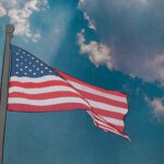 The US Flag flying against a blue sky with clouds.