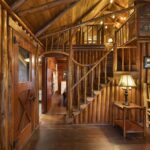 The interior of a Steiner Wooden Log Cabin, featuring a stair case with one twisted log as the railing.