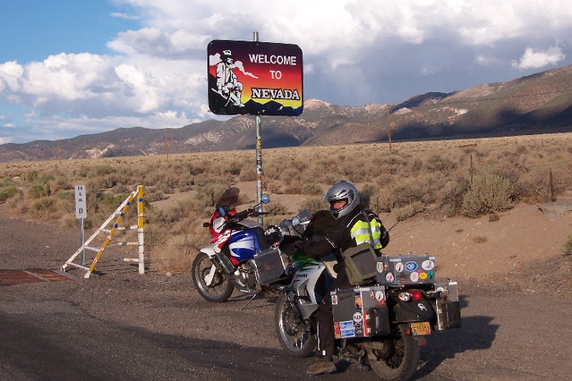 Motorcycles parked
        at a Welcome to Nevada sign on the highway